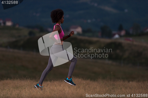 Image of Young African american woman jogging in nature