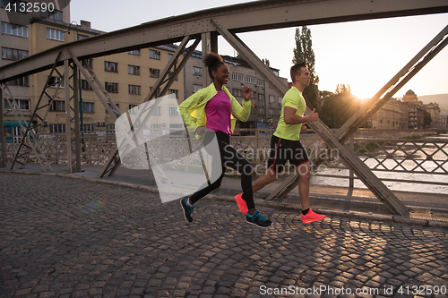 Image of young multiethnic couple jogging in the city