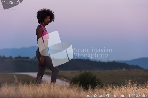 Image of Young African american woman jogging in nature