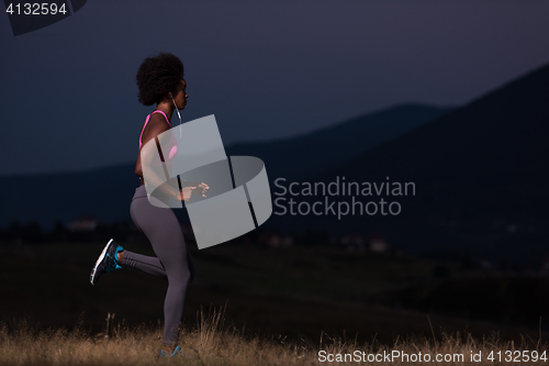 Image of Young African american woman jogging in nature