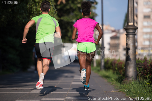 Image of young smiling multiethnic couple jogging in the city