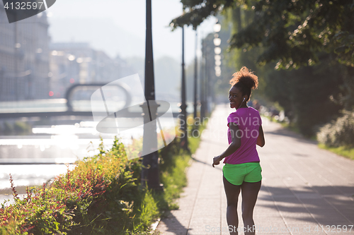 Image of african american woman jogging in the city