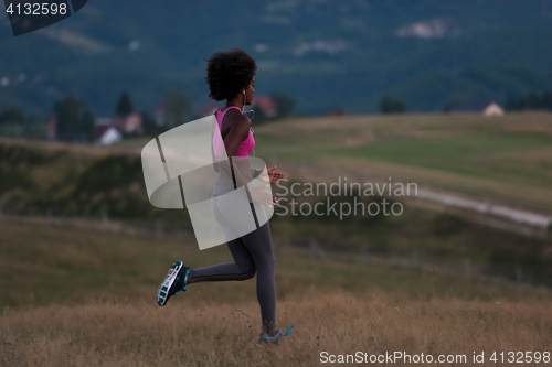 Image of Young African american woman jogging in nature