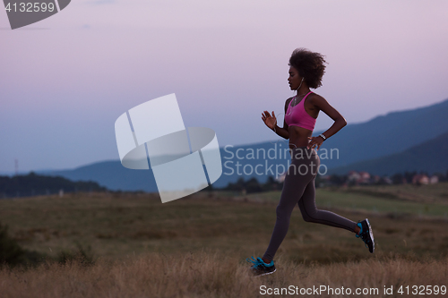 Image of Young African american woman jogging in nature