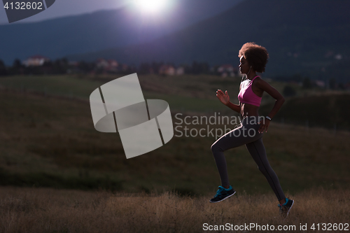 Image of Young African american woman jogging in nature