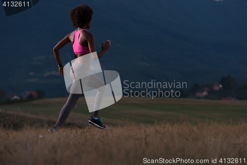 Image of Young African american woman jogging in nature