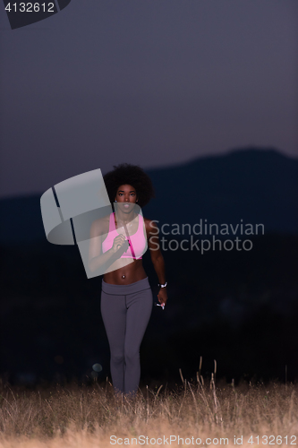 Image of Young African american woman jogging in nature