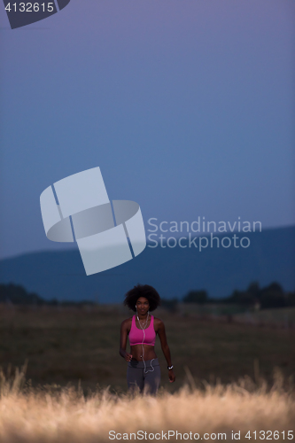 Image of Young African american woman jogging in nature