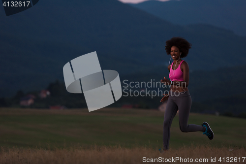 Image of Young African american woman jogging in nature