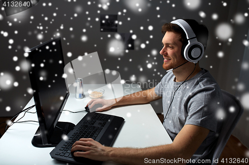 Image of man in headset playing computer video game at home