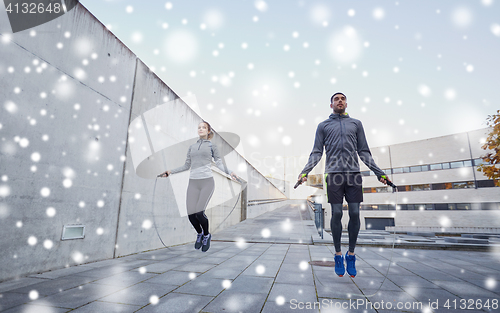 Image of man and woman exercising with jump-rope outdoors