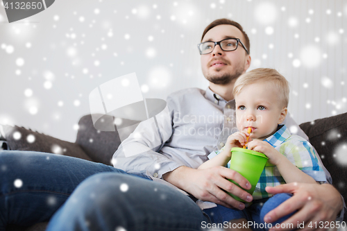 Image of father and little son drinking from cup at home
