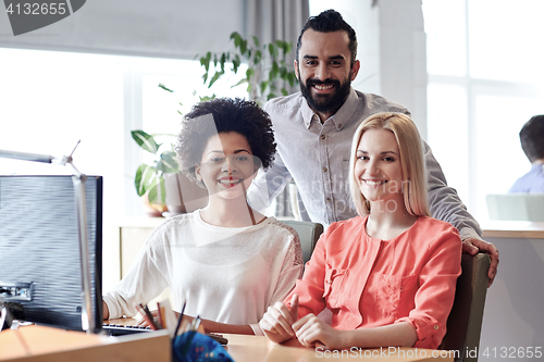 Image of happy creative team with computer in office