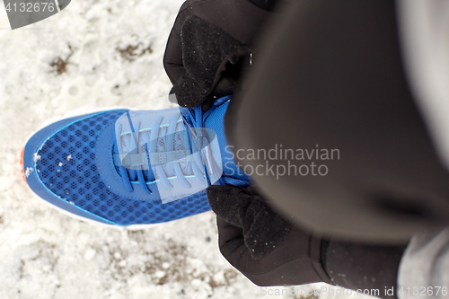 Image of close up of man tying shoe lace in winter outdoors