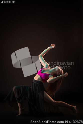 Image of Young beautiful dancer in beige dress dancing on black background