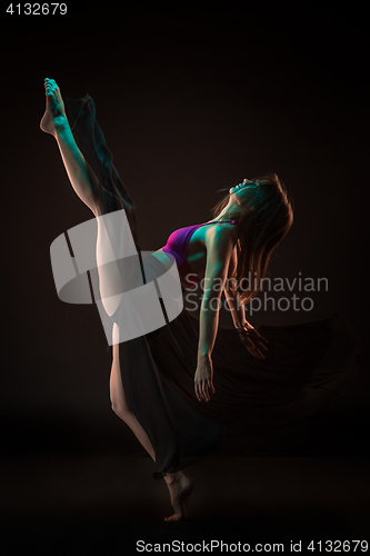 Image of Young beautiful dancer in beige dress dancing on black background