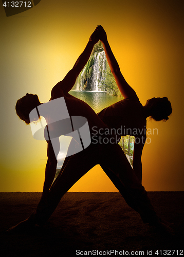 Image of Two people practicing yoga in the sunset light