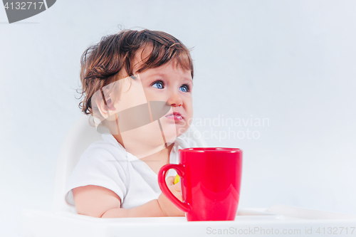 Image of Happy baby boy sitting and eating