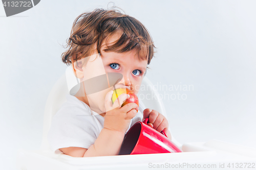 Image of Happy baby boy sitting and eating