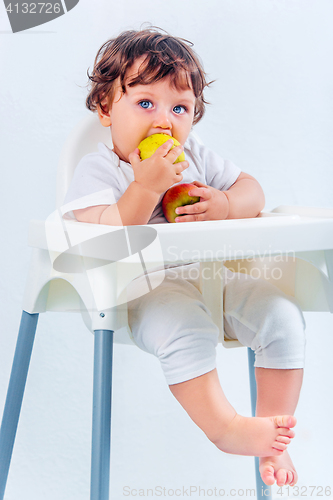 Image of Happy baby boy sitting and eating