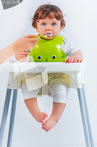 Image of Happy baby boy sitting and eating