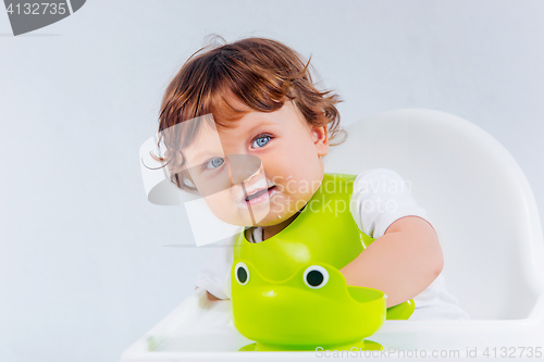 Image of Happy baby boy sitting and eating