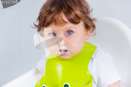 Image of Happy baby boy sitting and eating