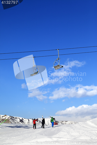 Image of Three skiers on slope at sun winter day