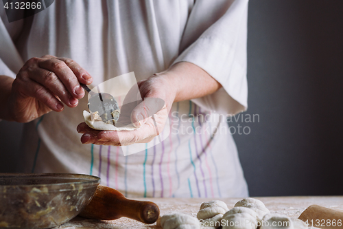 Image of Two hands making meat dumplings.