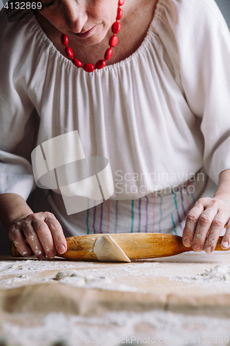 Image of Making meat dumpling with wooden rolling pin.