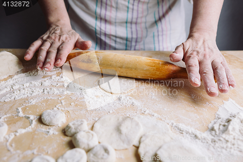 Image of Making meat dumpling with wooden rolling pin.