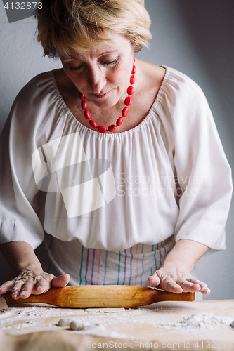 Image of Making meat dumpling with wooden rolling pin.