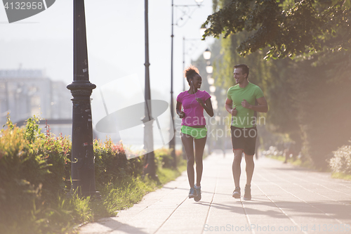 Image of young multiethnic couple jogging in the city
