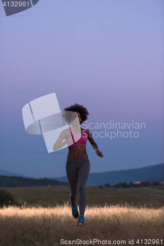 Image of Young African american woman jogging in nature