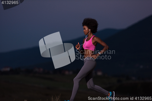 Image of Young African american woman jogging in nature