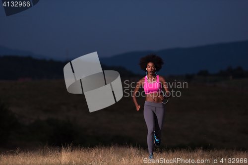 Image of Young African american woman jogging in nature