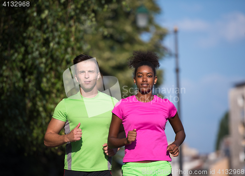 Image of young smiling multiethnic couple jogging in the city