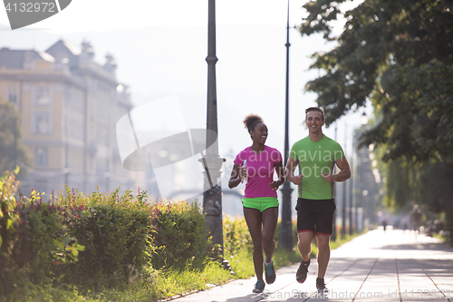 Image of young multiethnic couple jogging in the city