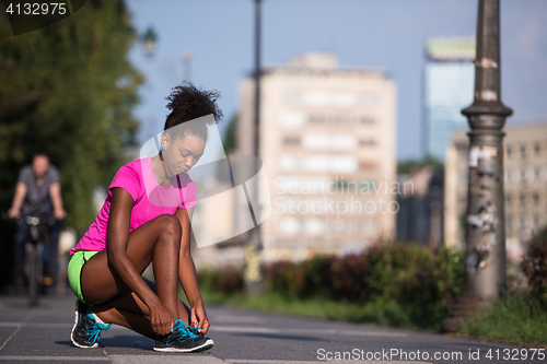 Image of African american woman runner tightening shoe lace