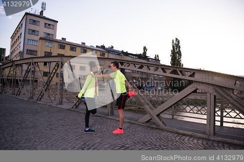 Image of jogging couple warming up and stretching in the city