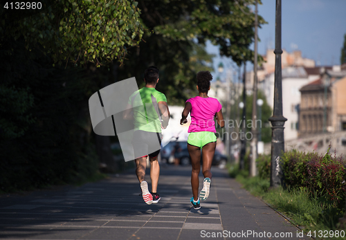 Image of young smiling multiethnic couple jogging in the city