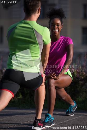 Image of jogging couple warming up and stretching in the city