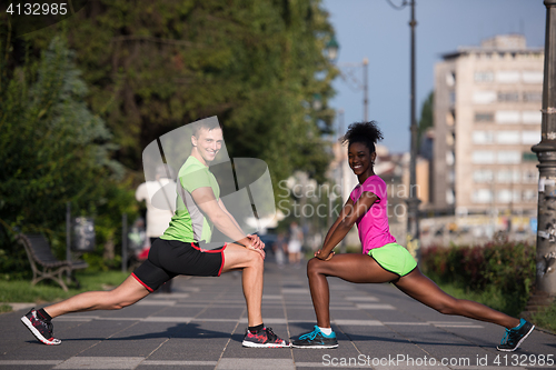 Image of jogging couple warming up and stretching in the city