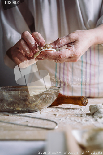 Image of Two hands making meat dumplings.