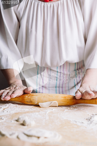 Image of Making meat dumpling with wooden rolling pin.