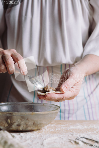 Image of Two hands making meat dumplings.