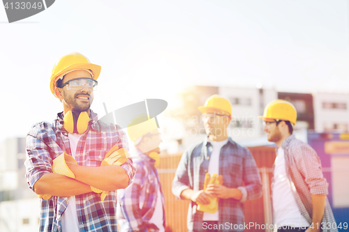 Image of group of smiling builders in hardhats outdoors