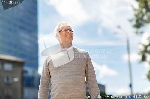 Image of senior man walking along summer city street