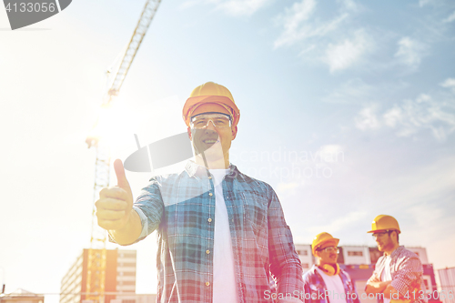 Image of group of smiling builders in hardhats outdoors