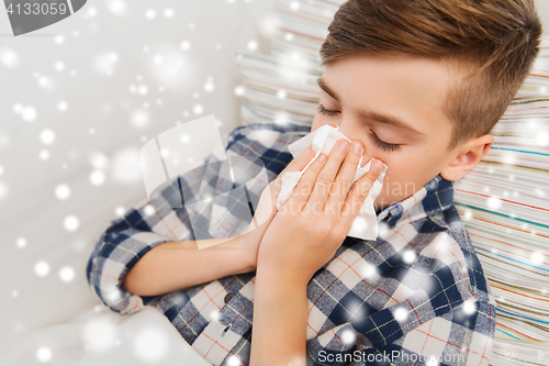 Image of close up of ill boy lying in bed and blowing nose